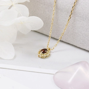 Close-up of vintage gold necklace with garnet pendant and ornate hollow crown filigree detail