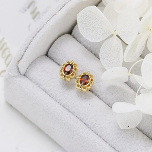 Macro shot of retro garnet stud earrings with gold lace hollow setting and 925 silver base