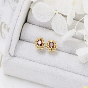 Macro view of vintage gold stud earrings with oval red stones on velvet jewelry box