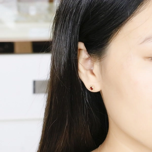 Close-up of elegant gold petal earrings with red garnet stones worn by a model