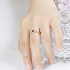 Close-up of a vintage S925 gilded lace ring featuring an oval red garnet on a finger