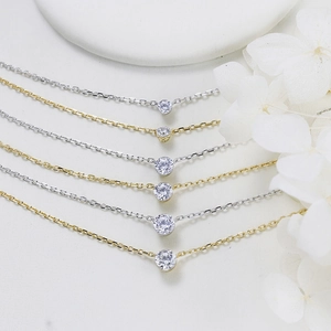 Close-up of gold and silver solitaire pendant necklaces with round cut moissanite stones