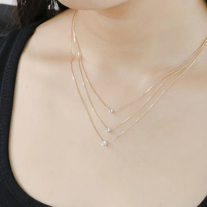 Detailed view of triple-layered gold necklaces with round cubic zirconia on a model neck