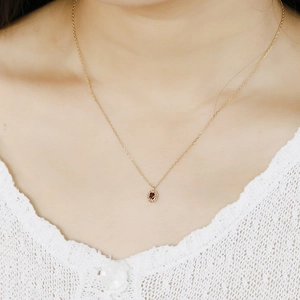 Macro view of a vintage garnet pendant necklace on a model wearing white lace