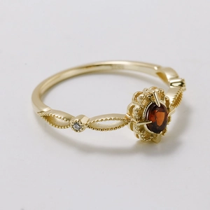 Vintage gold ring with oval red garnet and lace hollow design on white background