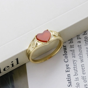 Detail of a heart-shaped red agate stone set in a vintage gold S925 silver ring on a book