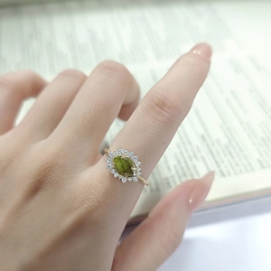 Primo piano di un anello con pietra verde taglio marquise e halo di zirconi su oro