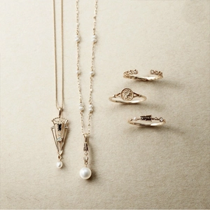 Draufsicht auf Vintage-Goldschmuck-Set mit Perlen und geprägtem Münzring-Detail