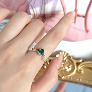 Anillo vintage con esmeralda en forma de corazón en plata dorada, mostrado en mano de modelo