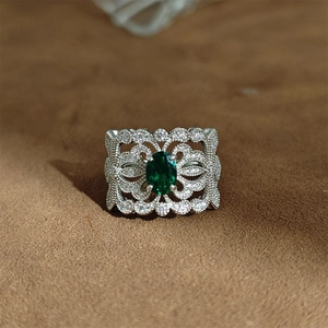 Détail macro d'une bague en argent S925 vintage avec émeraude et motifs ajourés ornementaux