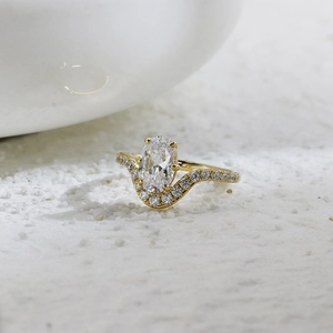 Macro detail of oval cut gemstone ring with gold plated micro-paved wavy band