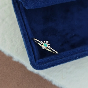 Macro shot of gold opal ring with blue-green fire and four white accent stones