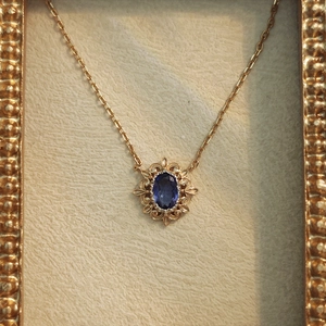 Gros plan sur le collier vintage doré avec pendentif tanzanite bleue et cadre dentelle