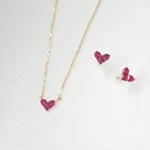 Detail view of heart-shaped ruby necklace and earrings set in minimalist gold plating