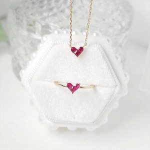 Detail of red heart gemstone necklace and ring set on white velvet jewelry box