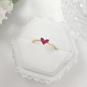 Detail of a heart-shaped ruby ring in 18K gold finish set in a white velvet box