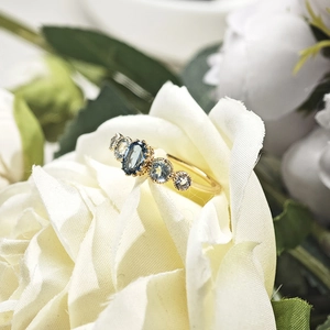 Close-up of gold ring with blue topaz stones set in a delicate rose flower