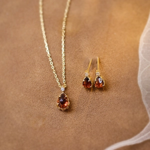 Detail of garnet teardrop pendant and stud earrings set in gold-plated silver