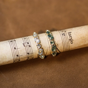 Vintage style gold rings set with moss agate and blue topaz on antique sheet music