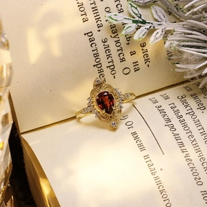 Macro shot of vintage gold-plated ring featuring pear-cut red garnet and intricate filigree