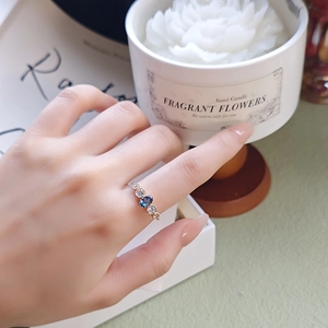 Close-up of a blue topaz ring in gold finish on a finger with lifestyle background