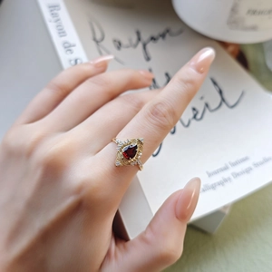 Close-up of vintage gold ring featuring a pear-shaped red garnet and halo zircons