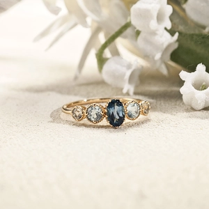 Natural Blue Topaz s925 silver ring with five oval gemstones on a sandy floral background