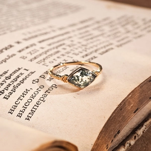 Vintage 14K gold plated 925 silver ring with lozenge-cut green moss agate on an antique book