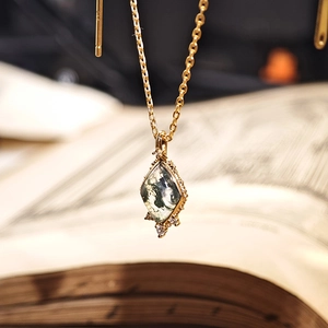 Macro view of gold plated necklace with a moss agate pendant on vintage book pages