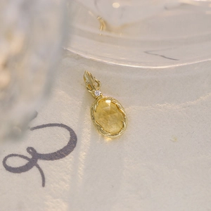 Dettaglio di un ciondolo in citrino ovale con placcatura in oro 18 carati e piccoli diamanti