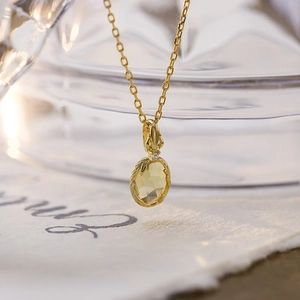 Dettaglio del ciondolo in citrino con incisione a foglia su una collana dorata raffinata