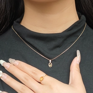 Dettaglio anello con citrino e collana con gemma verde su elegante tessuto nero