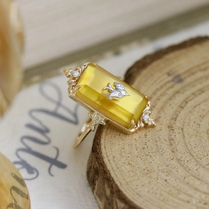 Macro shot of vintage rectangular yellow amber ring with silver bird and gold floral band