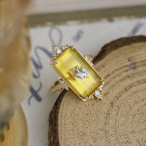 Macro view of vintage gold ring with rectangle yellow gemstone and silver bird detail