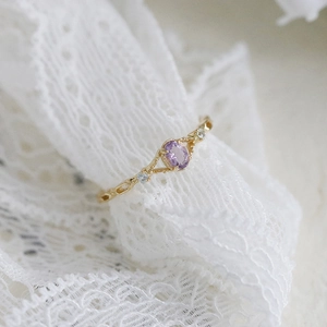 Elegante gouden ring met ovale amethist en zijstenen op een witte kanten achtergrond