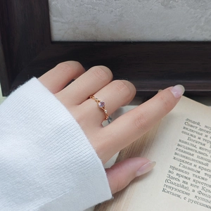 Detail van amethist edelsteen ring met gouden vlechtstructuur gedragen door model