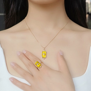 Detail of gold necklace and ring set with rectangular yellow gems and bird motifs