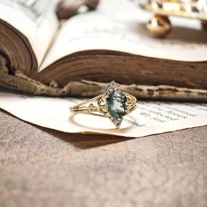 Macro detail of kite-cut moss agate ring with gold plated silver on vintage book page
