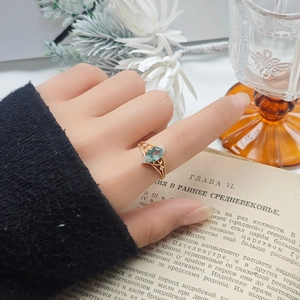 Detailed close-up of a geometric moss agate ring in gold on a vintage book backdrop