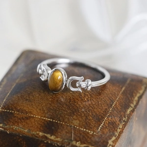Anillo vintage con ojo de tigre ovalado en plata y detalles de hebilla sobre un joyero