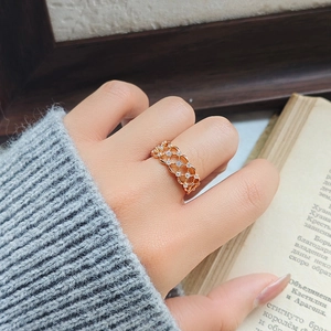 Bague en dentelle creuse en or rose avec petits cristaux portée sur le doigt