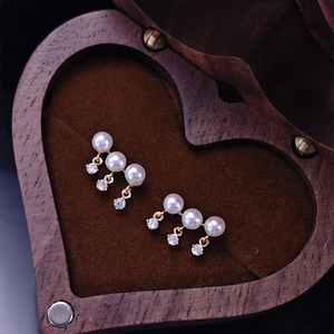 Detail of freshwater pearl tassel earrings with zircons on a heart wooden jewelry box