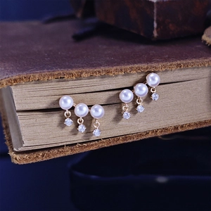 Detail of luxury freshwater pearl earrings with tassels and cubic zirconia on vintage books