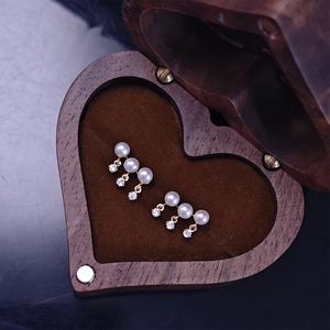 Detailed macro of gold freshwater pearl earrings with tassel cubic zirconia in wood box