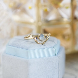 Macro view of gold wave ring with moonstone and blue side stones on blue velvet