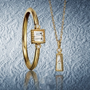 Nahaufnahme von vergoldetem Schmuckset mit Zirkonia im Baguetteschliff und Milgrain-Details