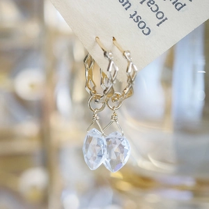 Détail macro de boucles d'oreilles créoles dorées avec gouttes de cristal de quartz