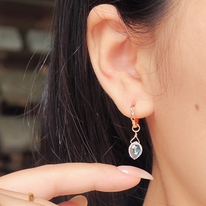 Détail de la boucle d'oreille dorée géométrique avec pendentif cristal goutte