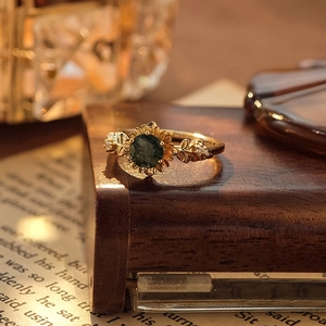 Vintage gold sunflower ring with green moss agate on a rustic wooden display stand