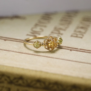 Makro-Detail eines Vintage-Goldrings mit Citrin und Olivin auf einem rustikalen Buch